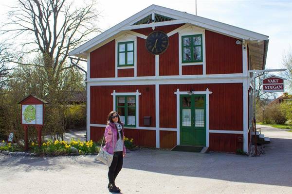 Tourist in front of a red wooden house with clock and Yalm Stugan sign