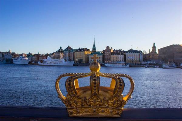 Gilded crown on Skeppsholmsbron bridge, Stockholm, with ships and colorful buildings