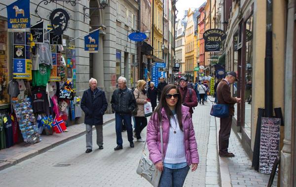 Woman in pink jacket walking down a busy pedestrian shopping street, Gamla Stan, Stockholm