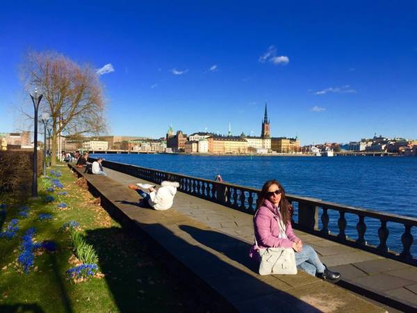 Woman sitting on Stockholm waterfront promenade, Riddarholmen across the water