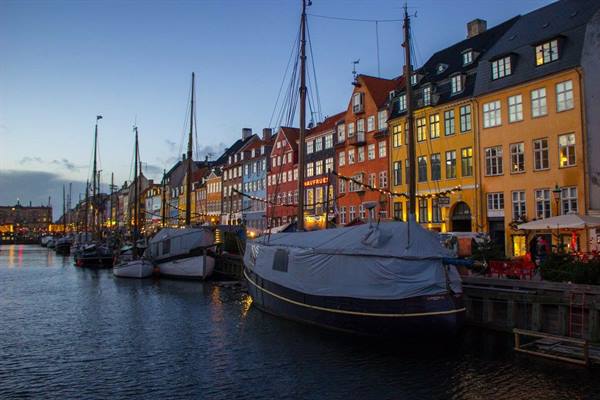 Boats moored at Nyhavn, Copenhagen, colorful townhouses lit at dusk