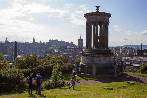Tourists on the grass beside Dugald Stewart Monument, Calton Hill, Edinburgh