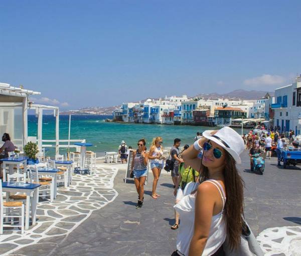 Tourist in white hat along Little Venice waterfront, Mykonos