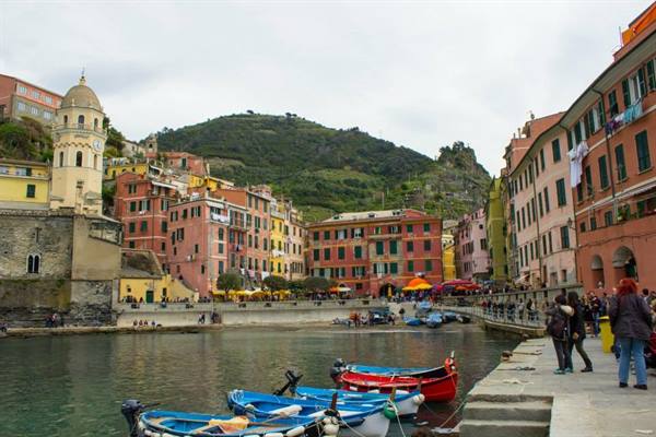 Vernazza: colorful boats in the harbor, pastel houses and tourists on the pier