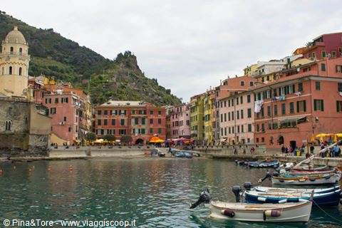 Boats moored in Vernazza harbor, colorful houses beneath the bell tower