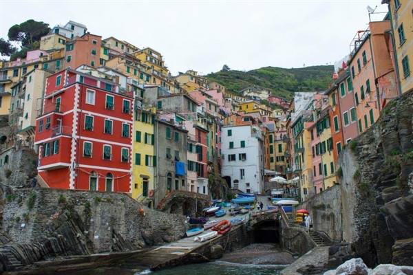 Riomaggiore, colorful houses towering over the canal with small boats