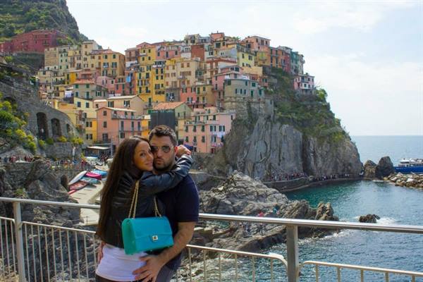 Couple embracing in front of Manarola's colorful houses by the sea
