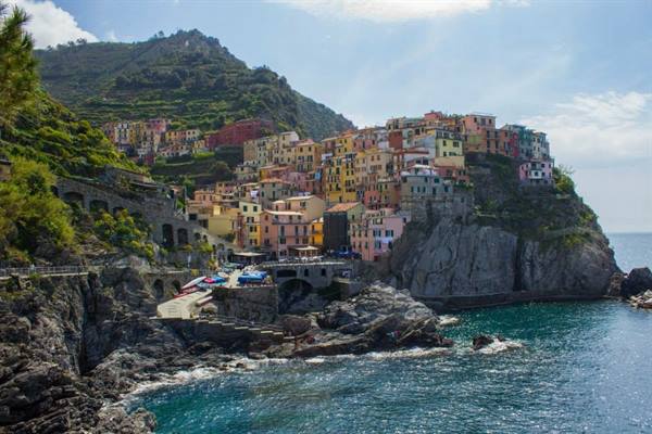 Colorful houses of Manarola perched on cliffs above the sea with boats