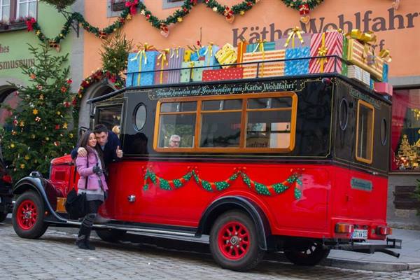 Tourists beside a red truck loaded with gifts outside Käthe Wohlfahrt
