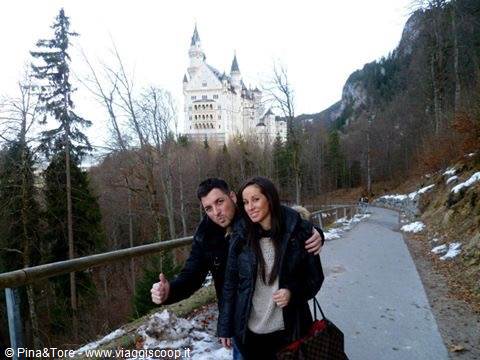 Smiling couple on the snowy path in front of Neuschwanstein Castle