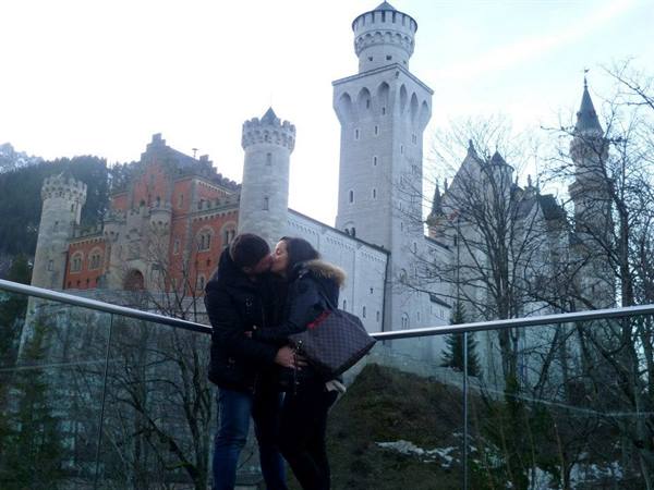 Couple kissing in front of Neuschwanstein Castle on a winter day