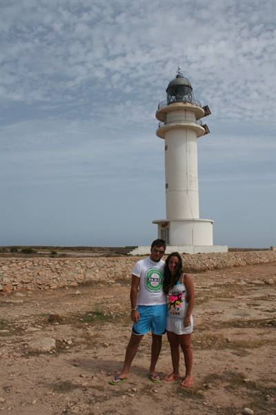 Couple posing in front of the white Cap de Barbaria lighthouse, Formentera