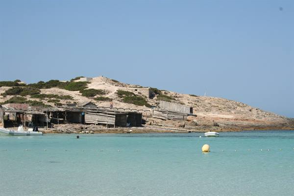 Wooden shacks and boats on Formentera's turquoise shore