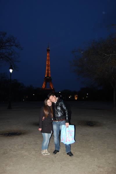 Couple embracing at night in front of the illuminated Eiffel Tower