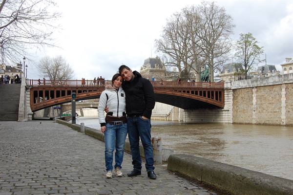 Couple hugging on the Seine embankment in front of Pont au Double, Paris
