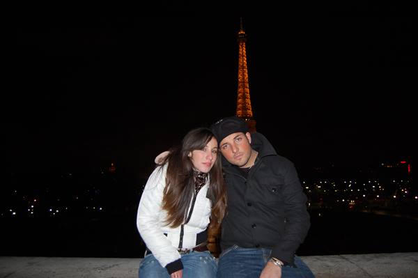 Couple sitting at night with the illuminated Eiffel Tower behind them