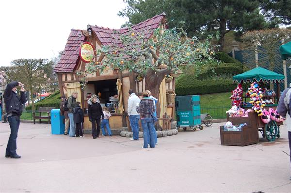 Visitors queuing at a timber cottage snack kiosk in an amusement park