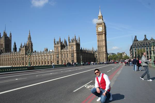 Tourist crouching on Westminster Bridge with Big Ben behind him