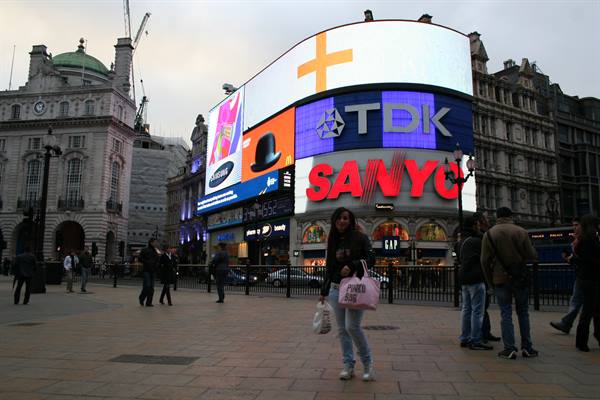 Piccadilly Circus, woman with pink bag walking past Sanyo and TDK billboards