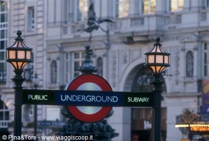 Underground sign at Piccadilly Circus between two lit lampposts
