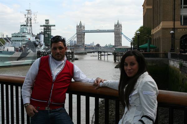 Couple leaning on the railing by the Thames, with Tower Bridge behind them
