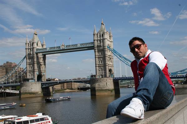Tourist sitting on a stone wall in front of Tower Bridge, London