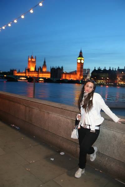 Girl leaning on the Thames embankment wall, Big Ben and Parliament lit behind