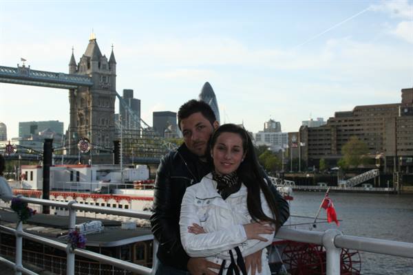 Couple embracing by the Thames, Tower Bridge and the Gherkin behind