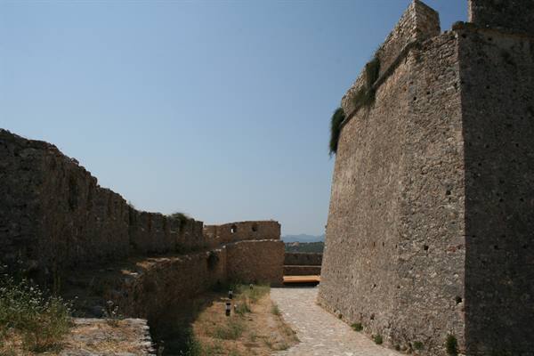 Stone fortress walls under blue sky, paved path between the bastions