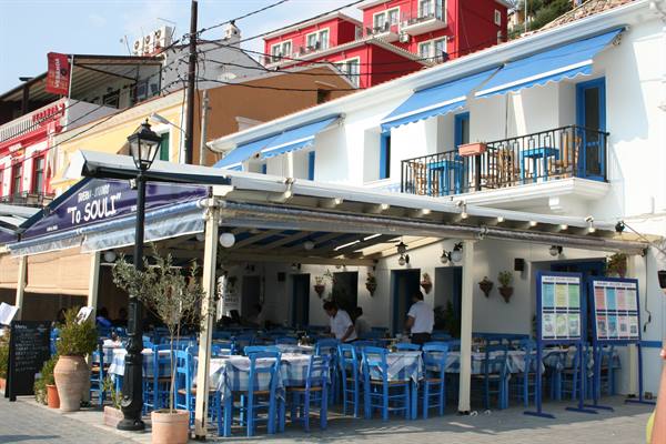 To Souli tavern with set tables, blue chairs and awnings in Paxos