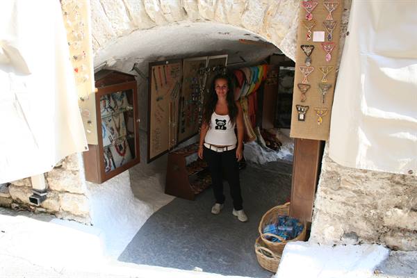 Woman standing at the entrance of a whitewashed stone souvenir shop