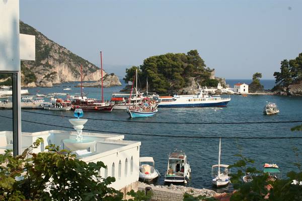 Boats anchored in Parga harbor among green rocks and white houses
