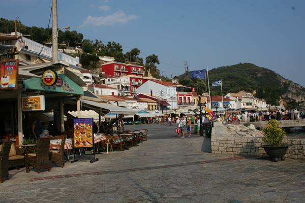 Waterfront cafés with outdoor tables and tourists in a Greek town
