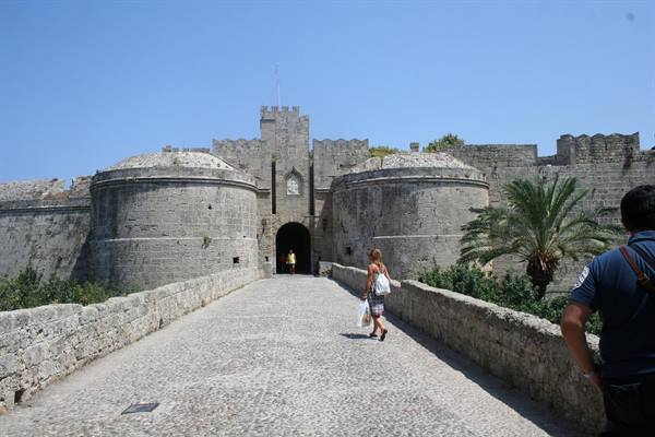 Tourist walks toward the medieval Old Town gate of Rhodes