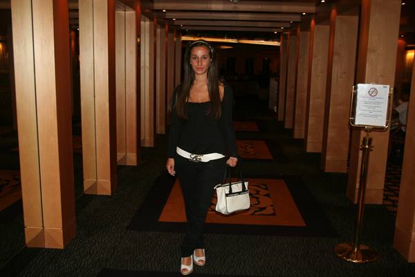 Woman in black with white belt walking through wood-paneled corridor