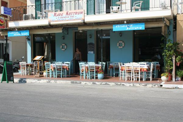 Empty tables outside the blue Mare Nostrum taverna on a quiet street