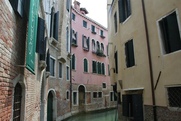 Pink and brick buildings overlooking a narrow canal in Venice
