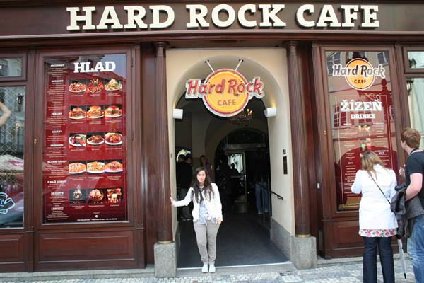 Woman in white at the Hard Rock Cafe entrance, glowing signs and menus