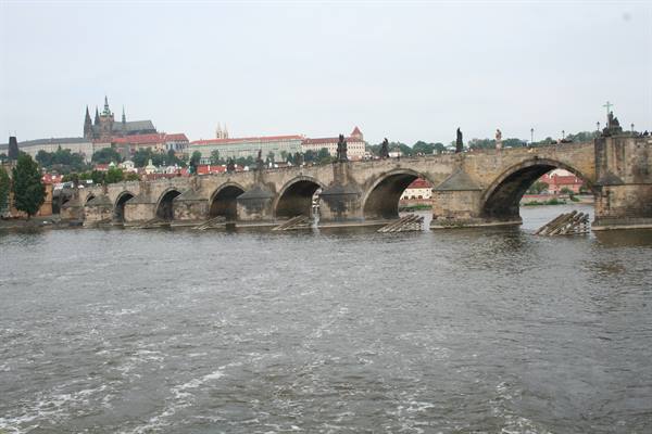 Charles Bridge stone arches with statues over the Vltava, Prague Castle behind
