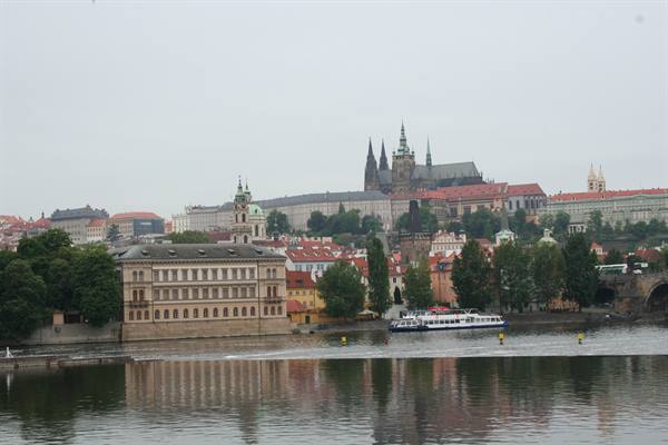 Boat on the Vltava river in front of Prague Castle under grey skies