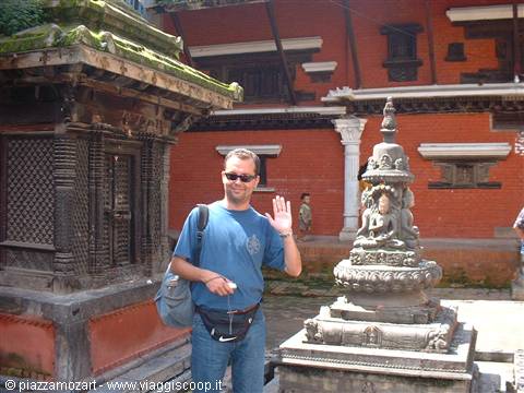 Tourist waving beside a stone shrine and red brick temples, Kathmandu