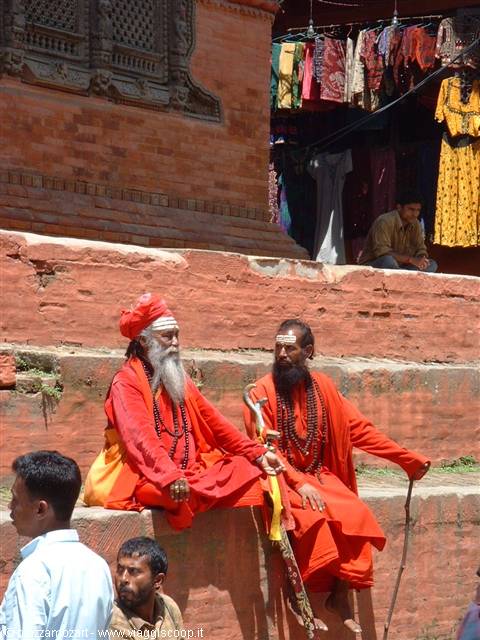 Two sadhus in orange robes sitting on red brick steps at Pashupatinath