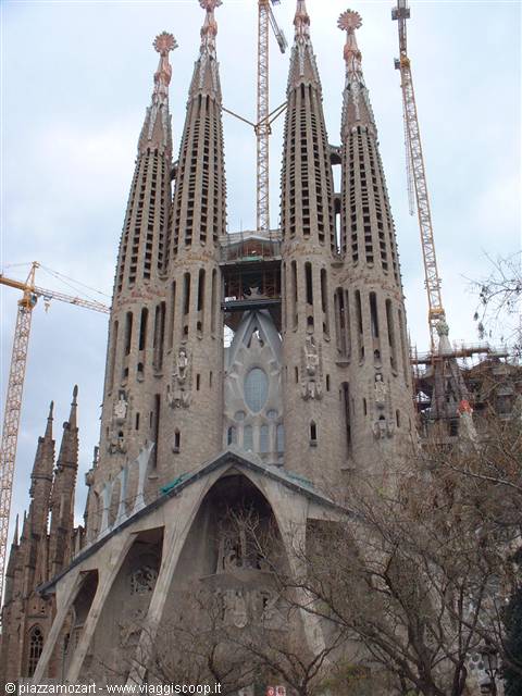 Sagrada Familia in Barcelona, stone spires among cranes under grey sky