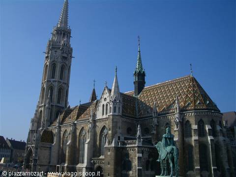 Matthias Church in Budapest, gothic bell tower and colorful tiled roofs under blue sky
