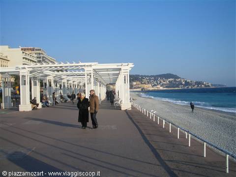 Couple strolling under the white pergola of the Promenade des Anglais in Nice