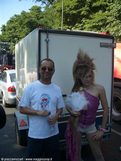 Man with sunglasses next to a drag queen in front of a white trailer