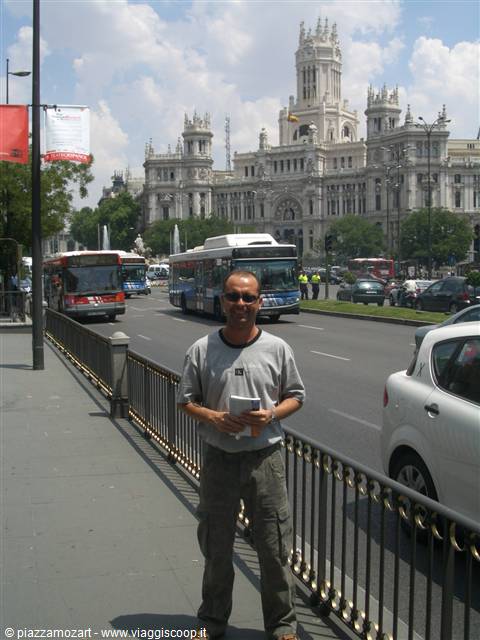 Tourist with map near Cibeles fountain, Palacio de Cibeles and city buses behind him