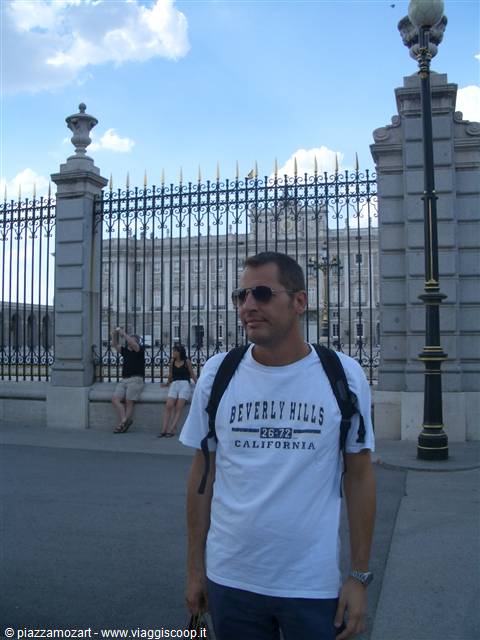 Tourist with backpack in front of the Royal Palace of Madrid gates