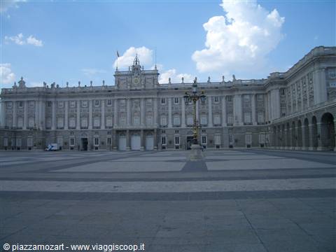Facade of the Royal Palace of Madrid with lampposts and empty square, cloudy sky