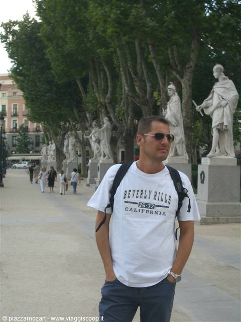 Tourist with backpack among marble royal statues, Madrid statue walk